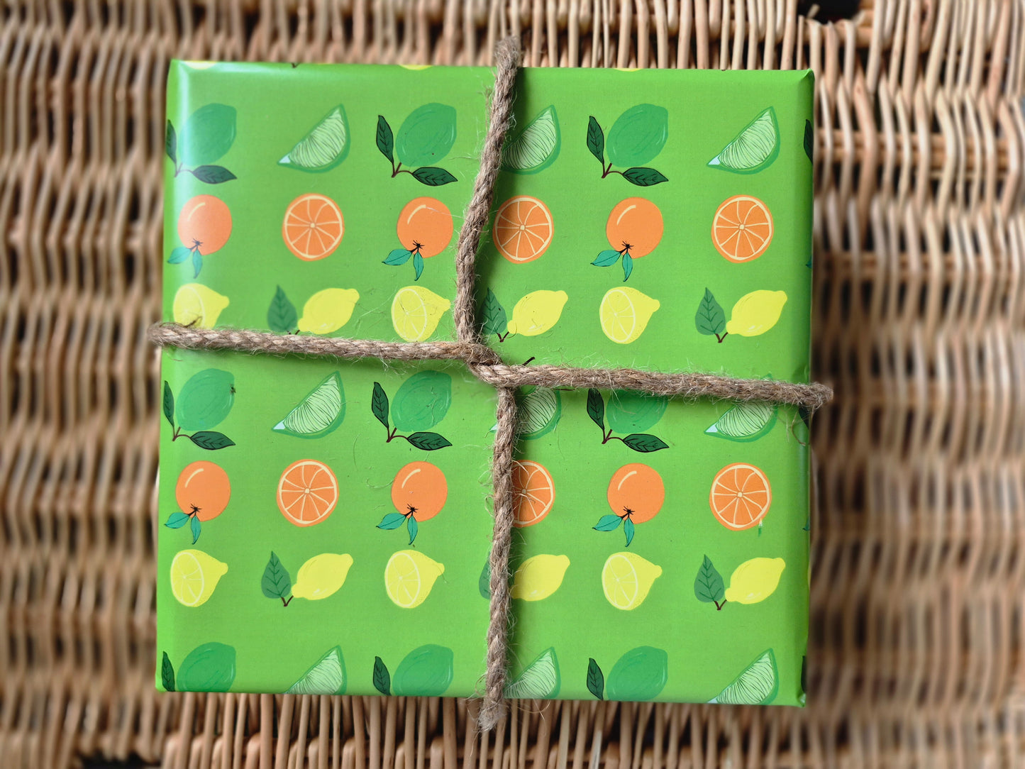 Green wrapping paper featuring a hand-drawn citrus fruit pattern of lemons, limes and oranges