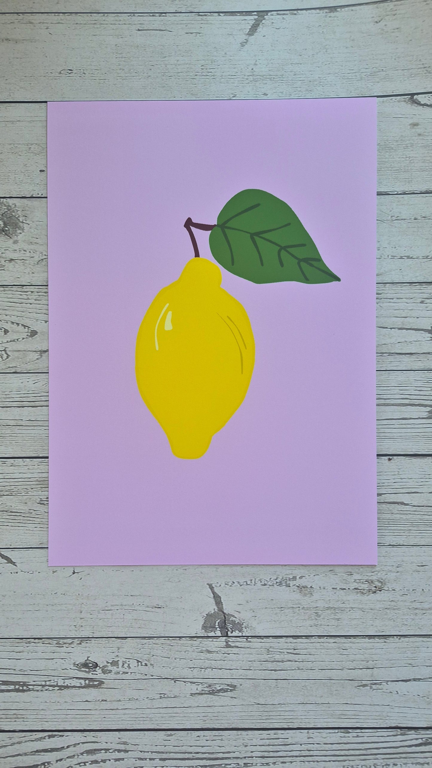 Yellow lemon with a green leaf on a purple card against a wooden background