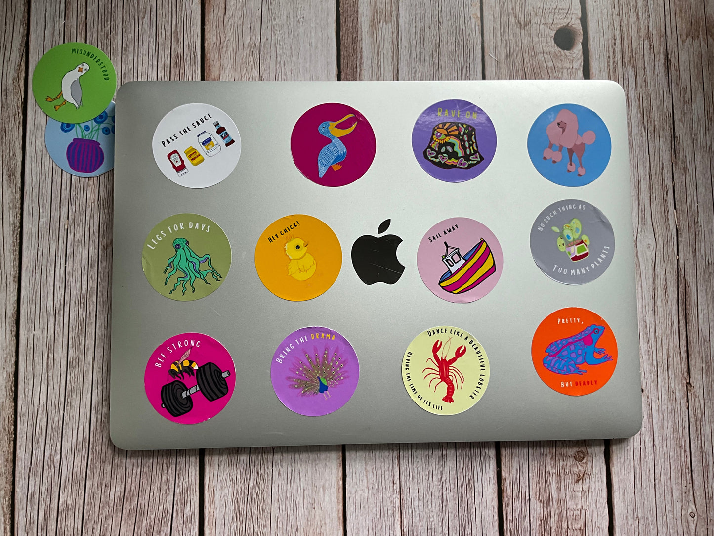 Laptop with various colorful stickers on a wooden surface