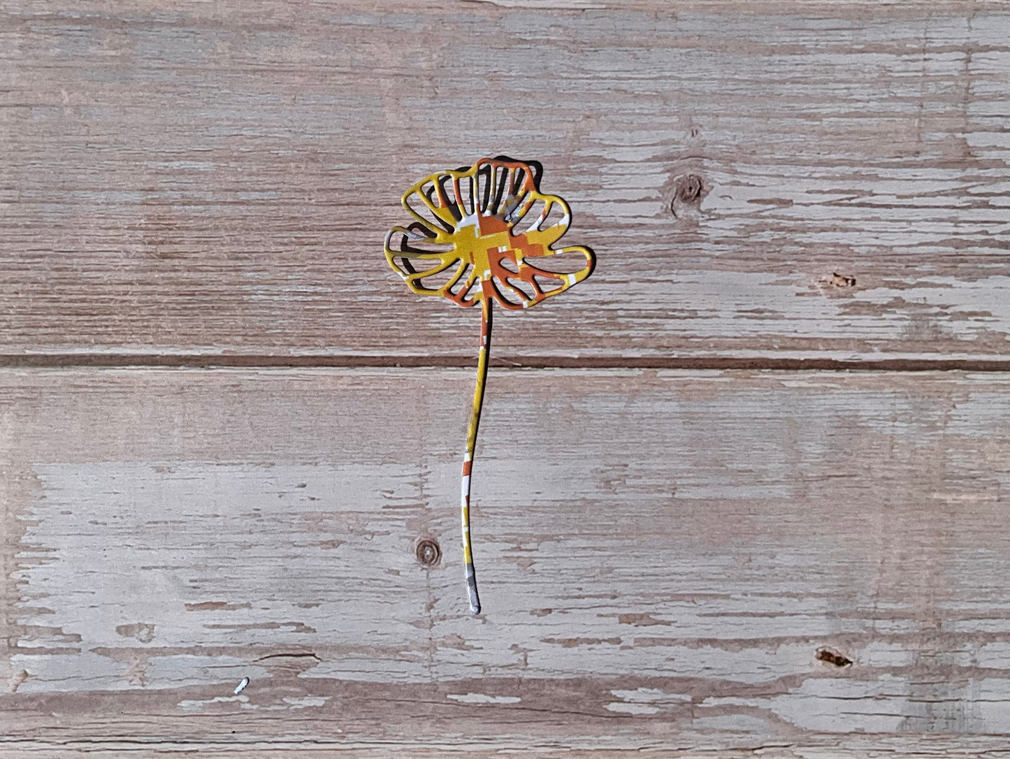 Yellow, orange and grey flower vinyl sticker on a wooden background