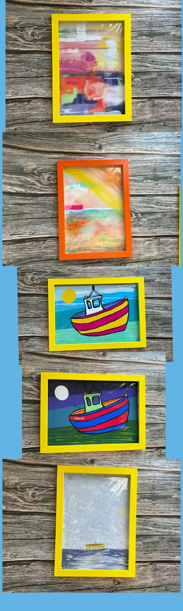 A row of travel art prints in frames on a wooden surface