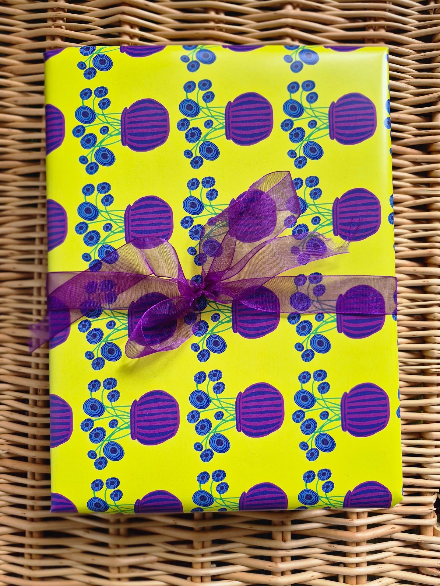 Yellow wrapping paper featuring a purple vase and blue poppies hand illustrated design