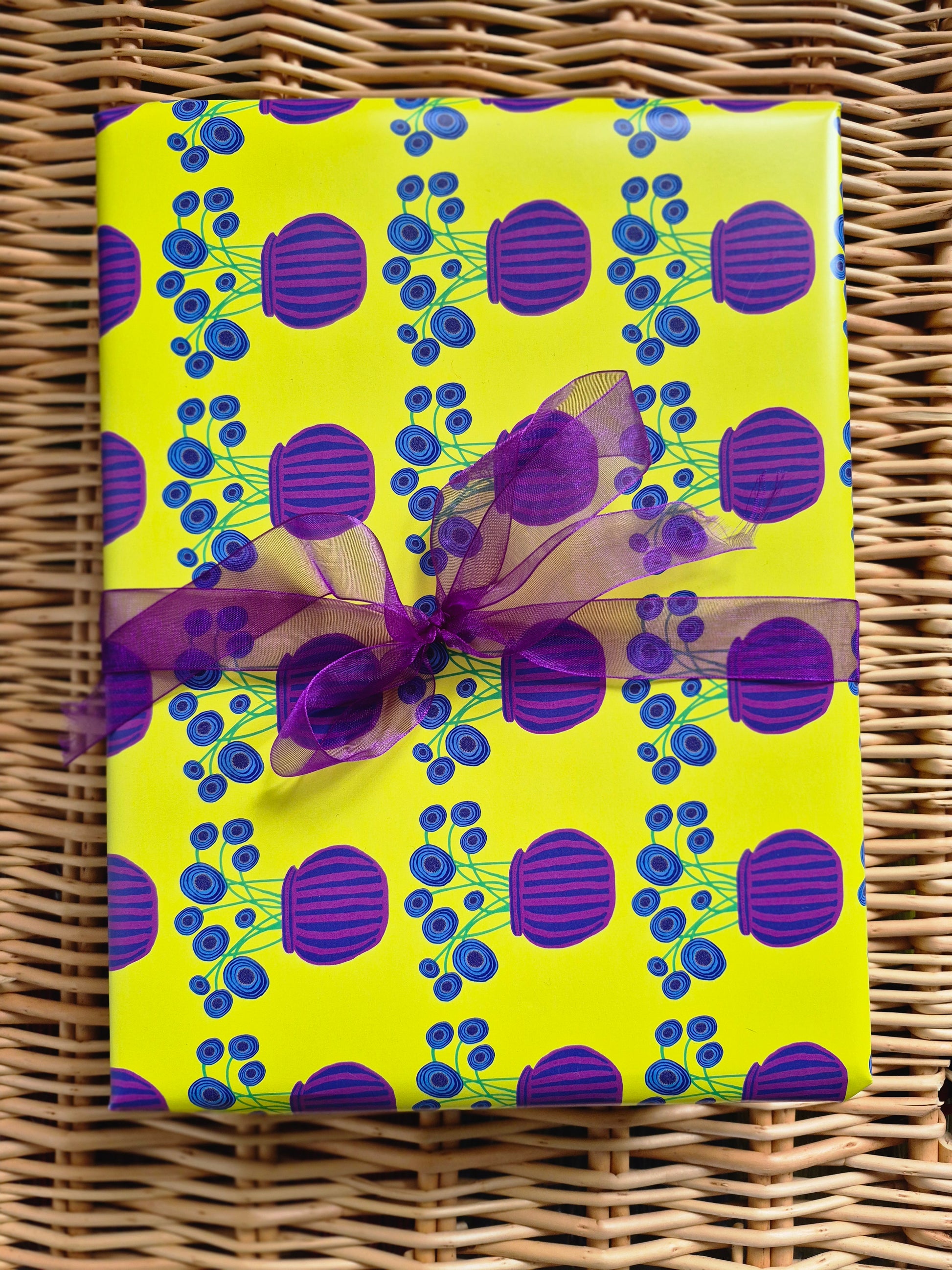 Yellow wrapping paper featuring a purple vase and blue poppies hand illustrated design