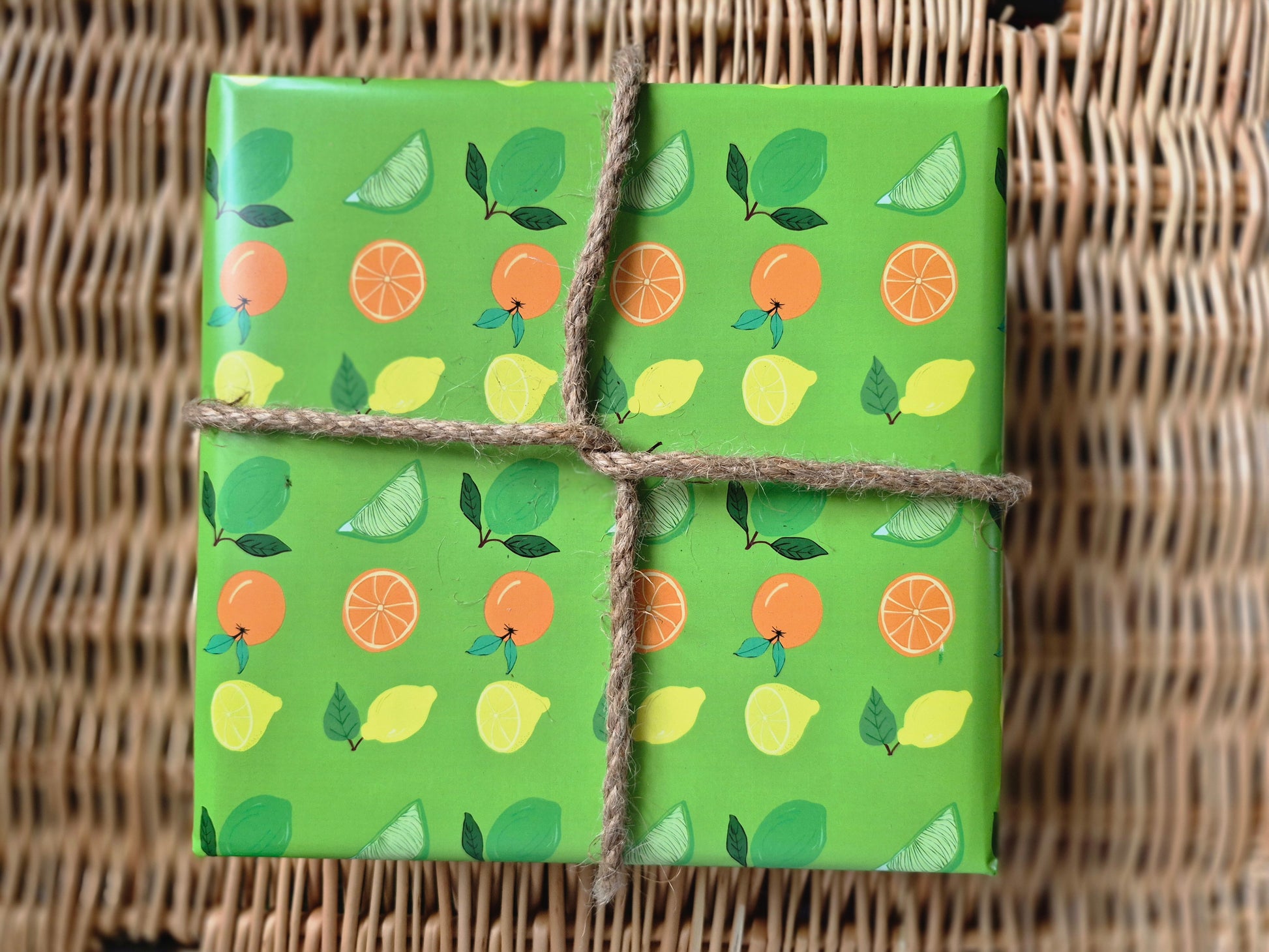 Green wrapping paper featuring a hand-drawn citrus fruit pattern of lemons, limes and oranges