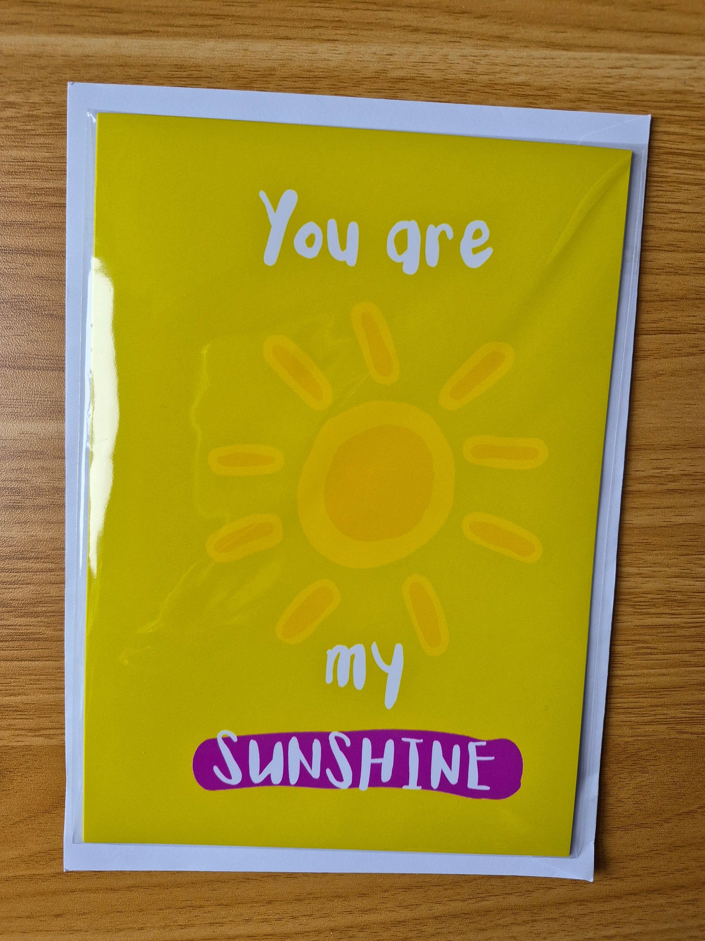 Card with a sun illustration and text 'You are my sunshine' on a wooden surface