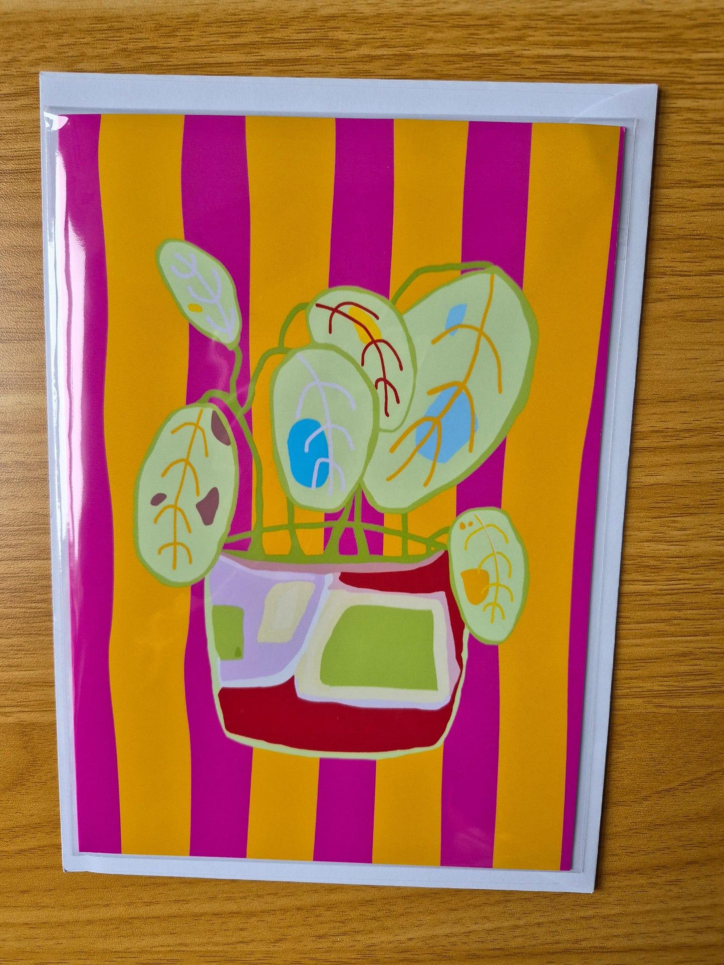Fun botanical greetings card with a plant pot design on an orange and pink striped background.