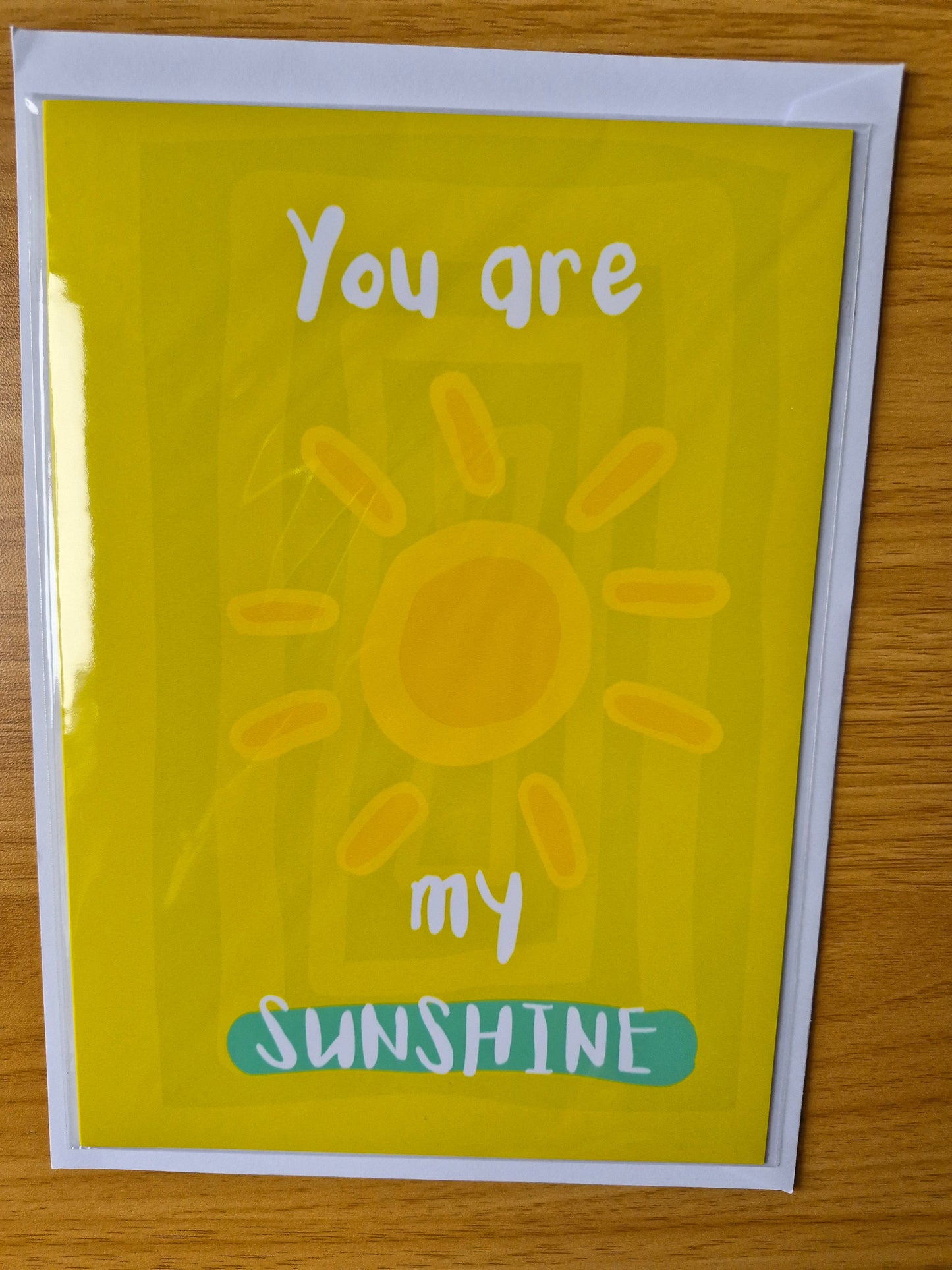 Card with a sun illustration and text 'You are my sunshine' on a wooden surface