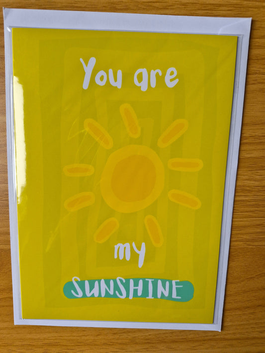 Card with a sun illustration and text 'You are my sunshine' on a wooden surface