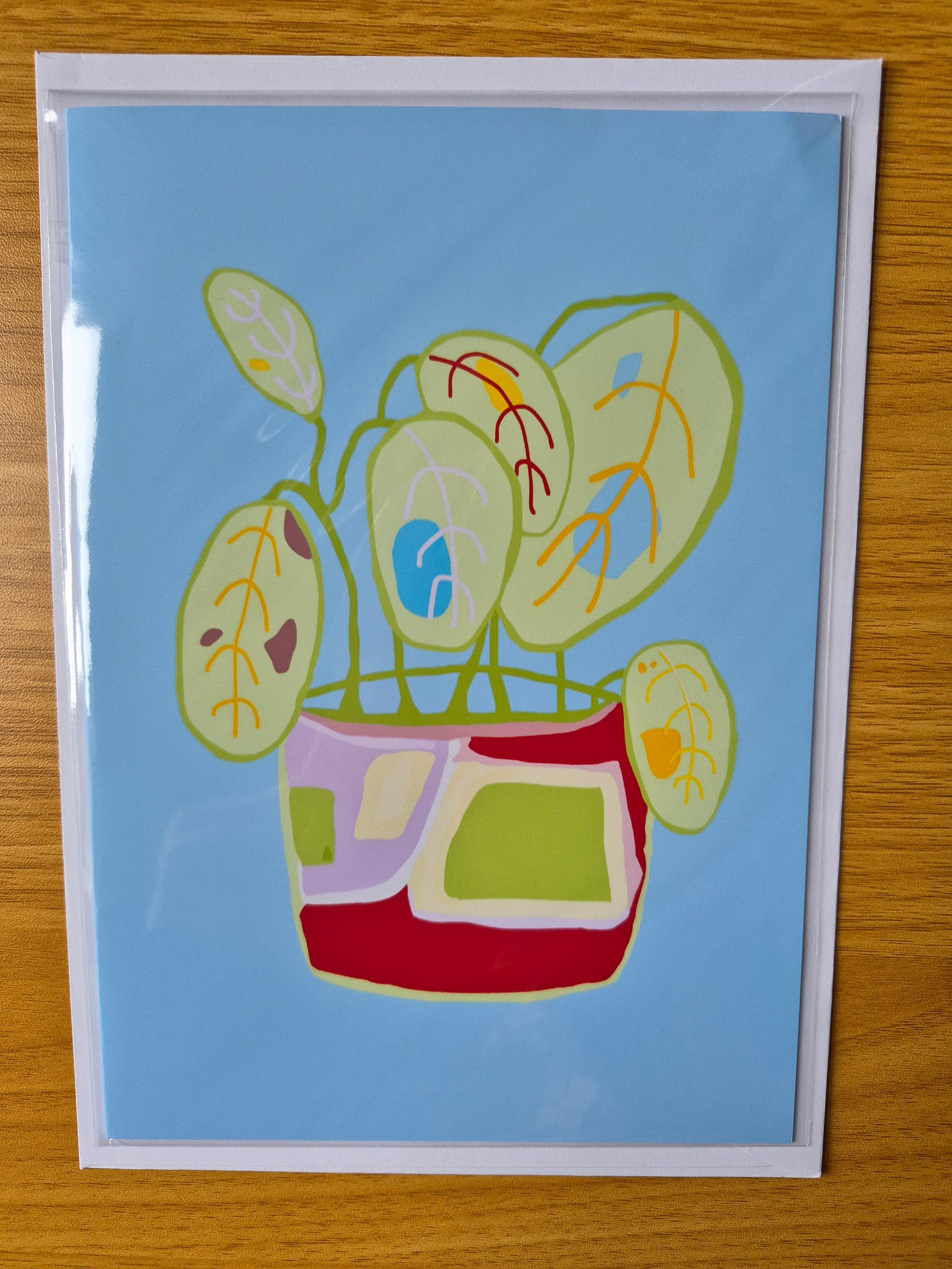 Colourful botanical greetings card with a plant pot design on blue background.