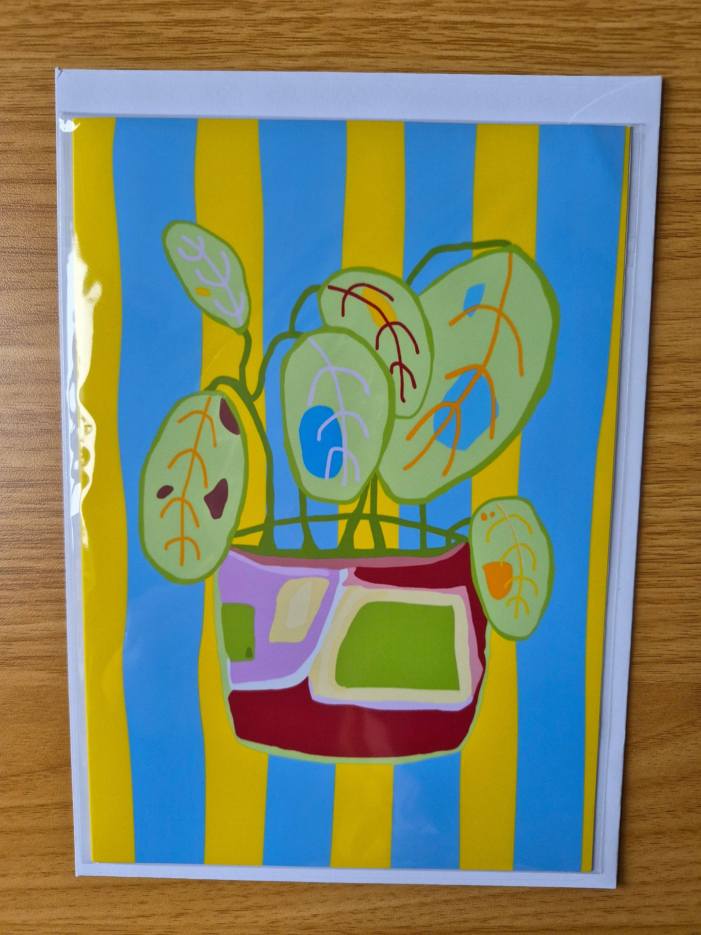 Colourful botanical greetings card with a plant pot design on a yellow and blue striped background.