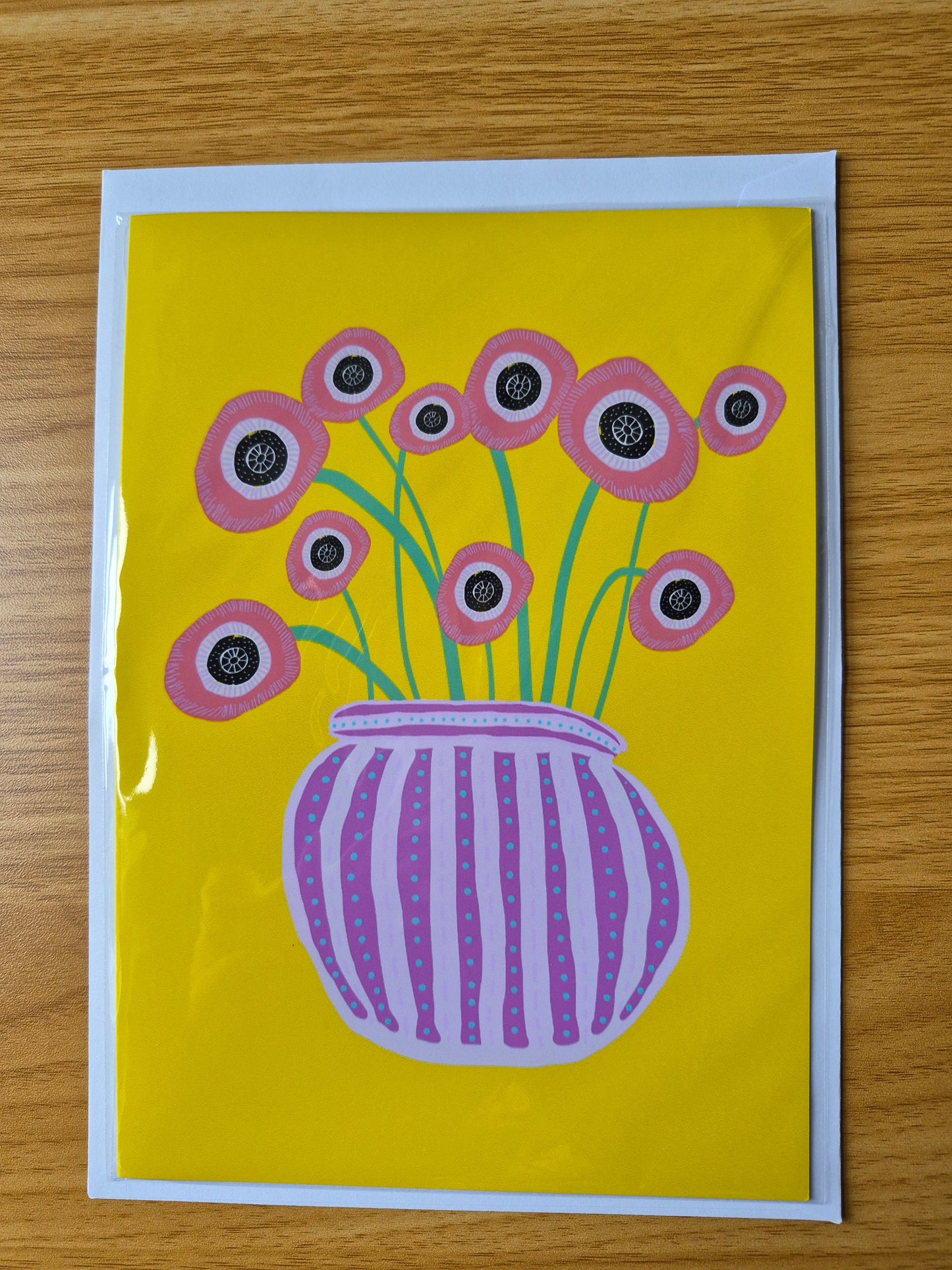 Greetings card featuring hand drawn red poppies in a purple striped vase on a yellow background.