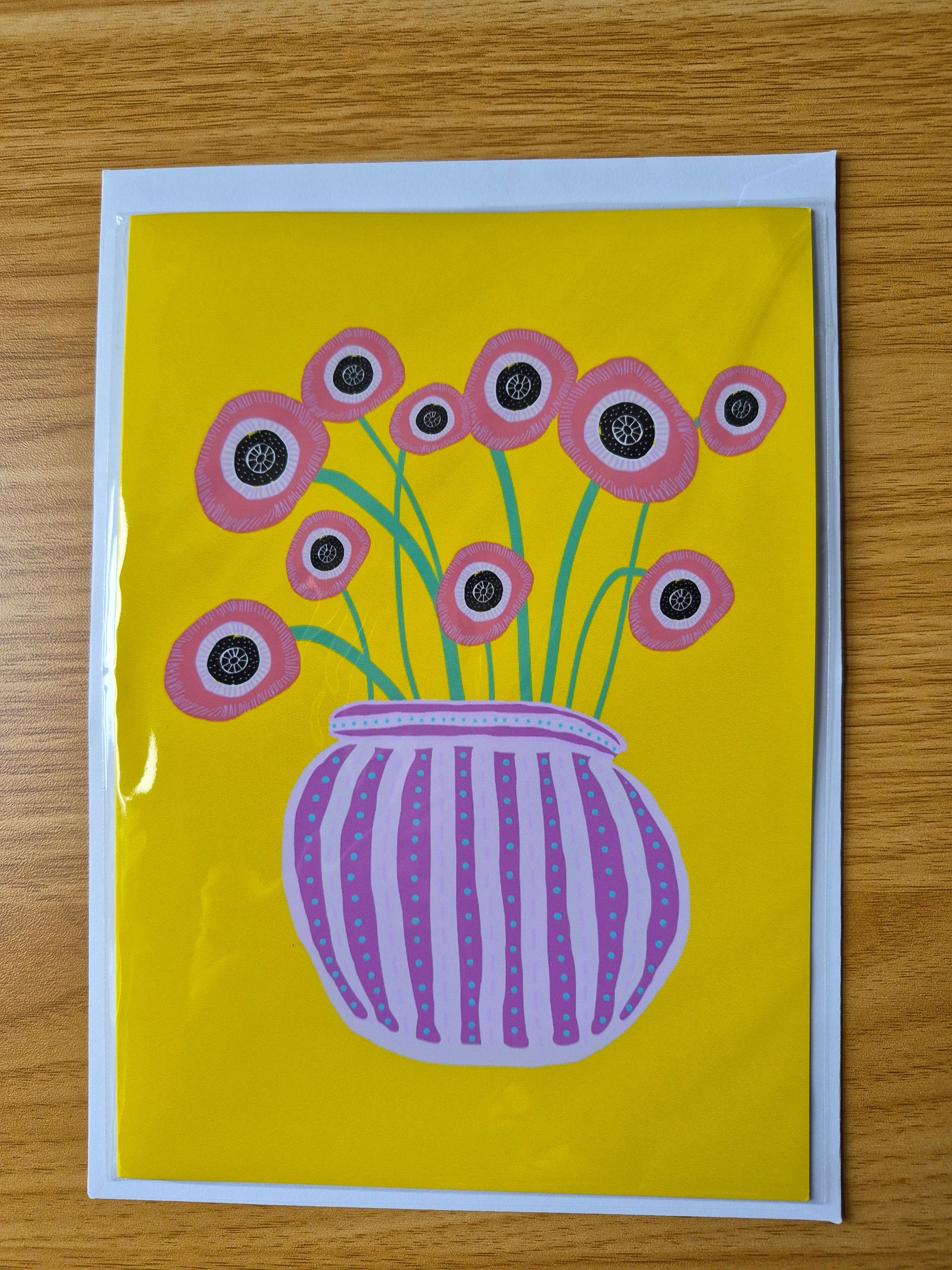 Greetings card featuring hand drawn red poppies in a purple striped vase on a yellow background.