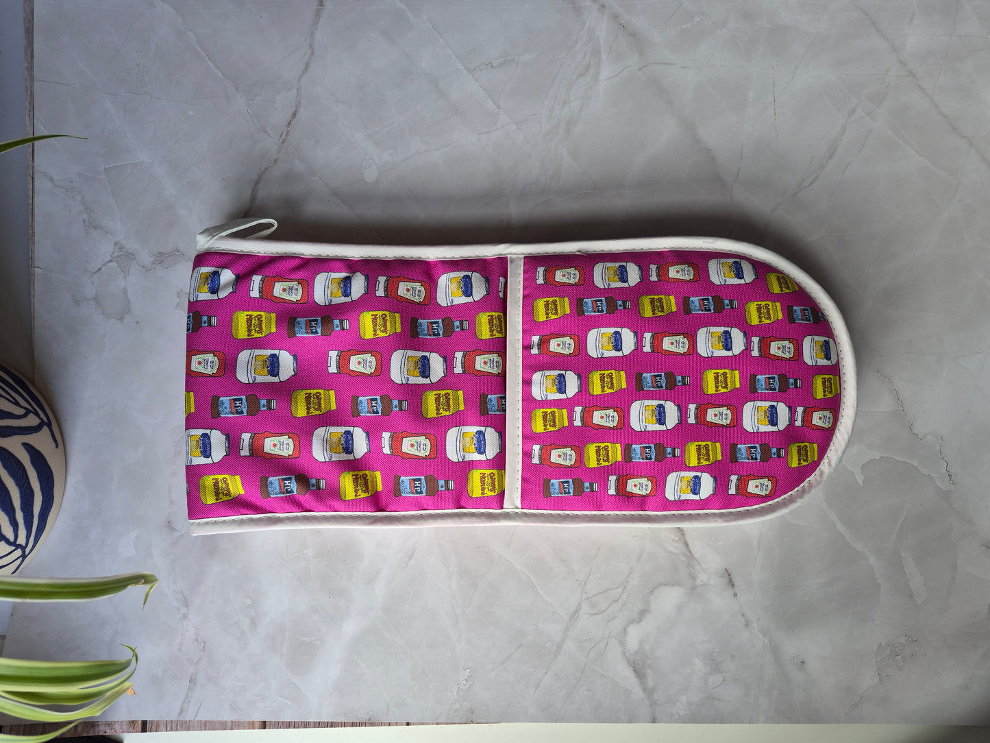 Bright pink double oven gloves with a table sauces print design.