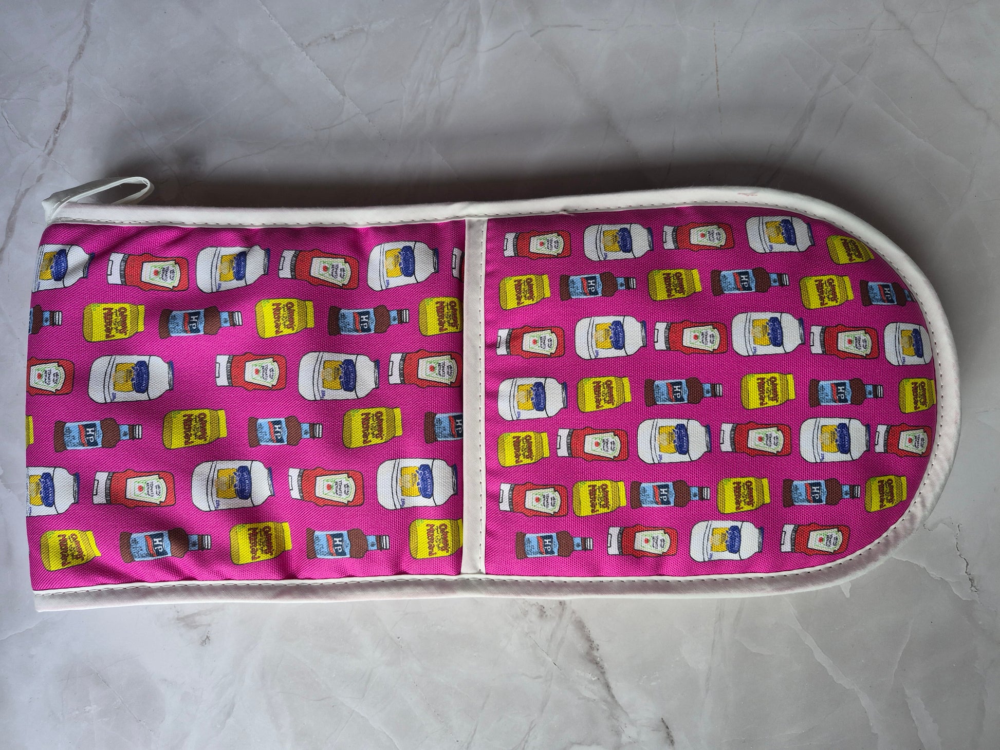 Hot pink double oven gloves with hanging loop and a ketchup & mustard print.