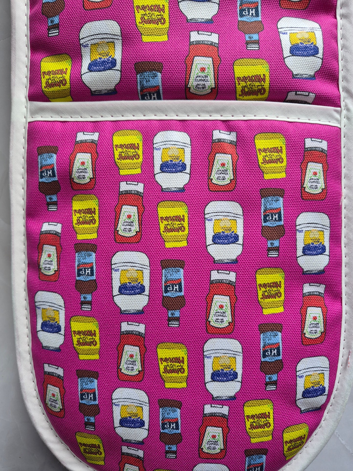 Close up of pink double oven gloves design depicting a ketchup, mayo, brown sauce & mustard print.