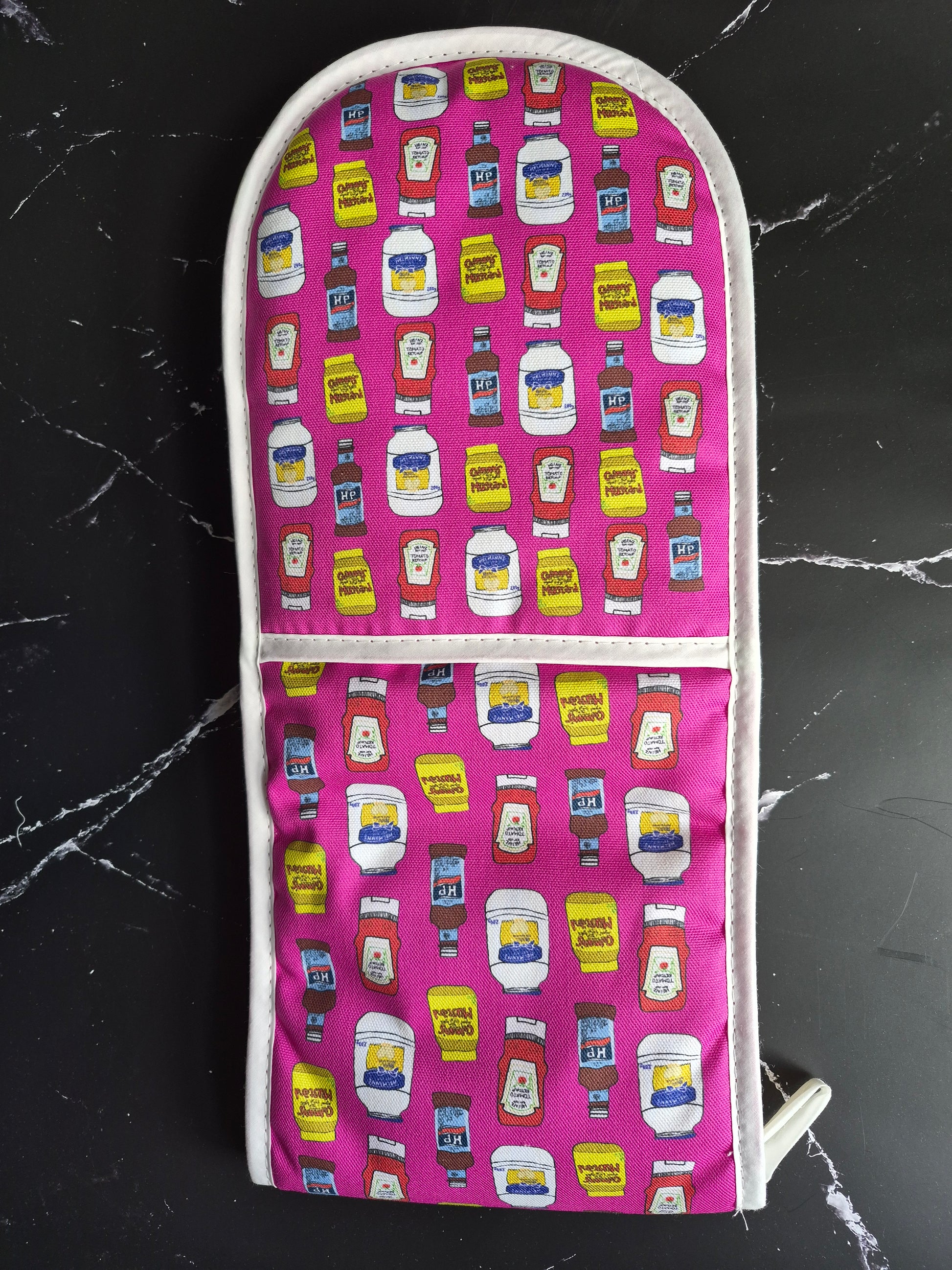 Pink printed oven gloves on a black marble counter.