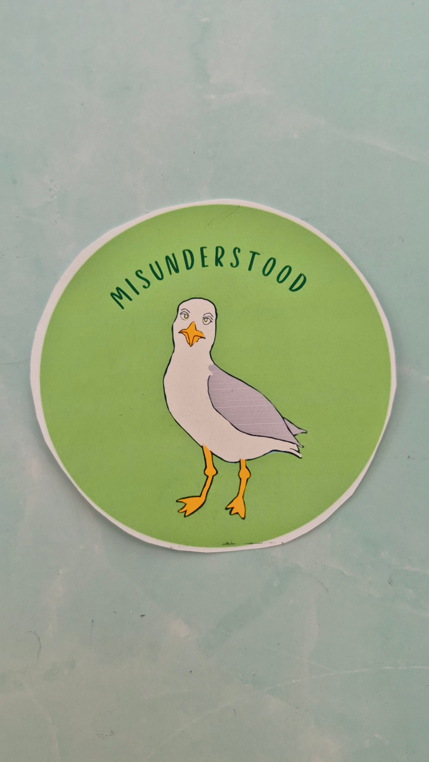 Circular vinyl sticker with a seagull illustration and text on a green background
