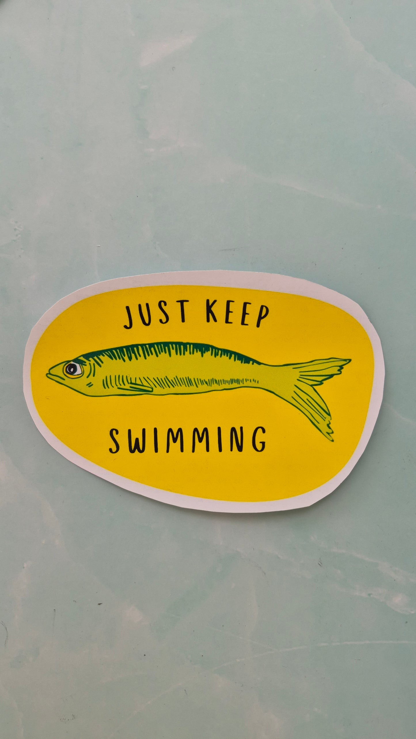 Vinyl sticker with a fish illustration and 'Just Keep Swimming' text on a yellow background