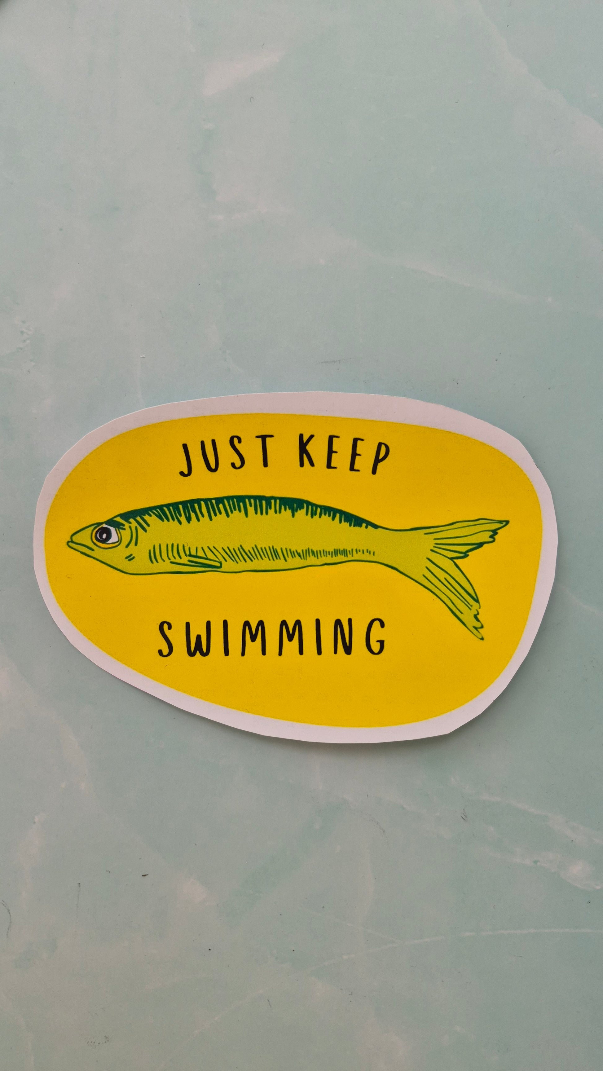 Vinyl sticker with a fish illustration and 'Just Keep Swimming' text on a yellow background