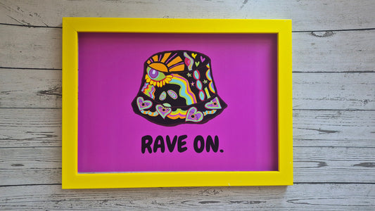 Framed artwork with a colourful bucket hat design and 'RAVE ON.' text on a pink/purple background.