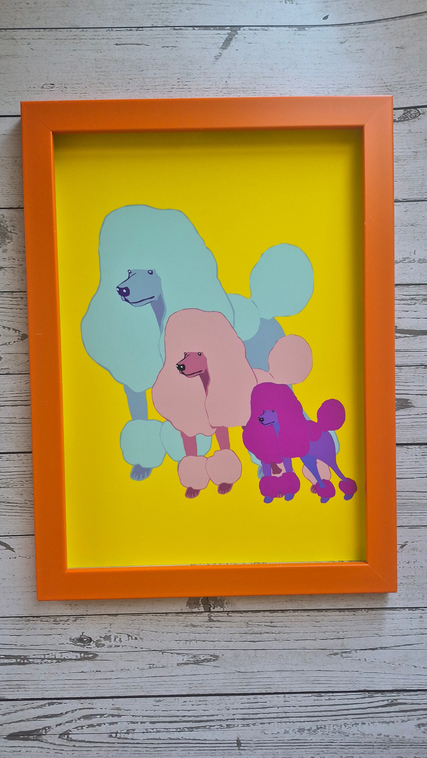 Framed abstract poodle artwork with colorful poodle dogs on a yellow background. Framed in an orange frame. 