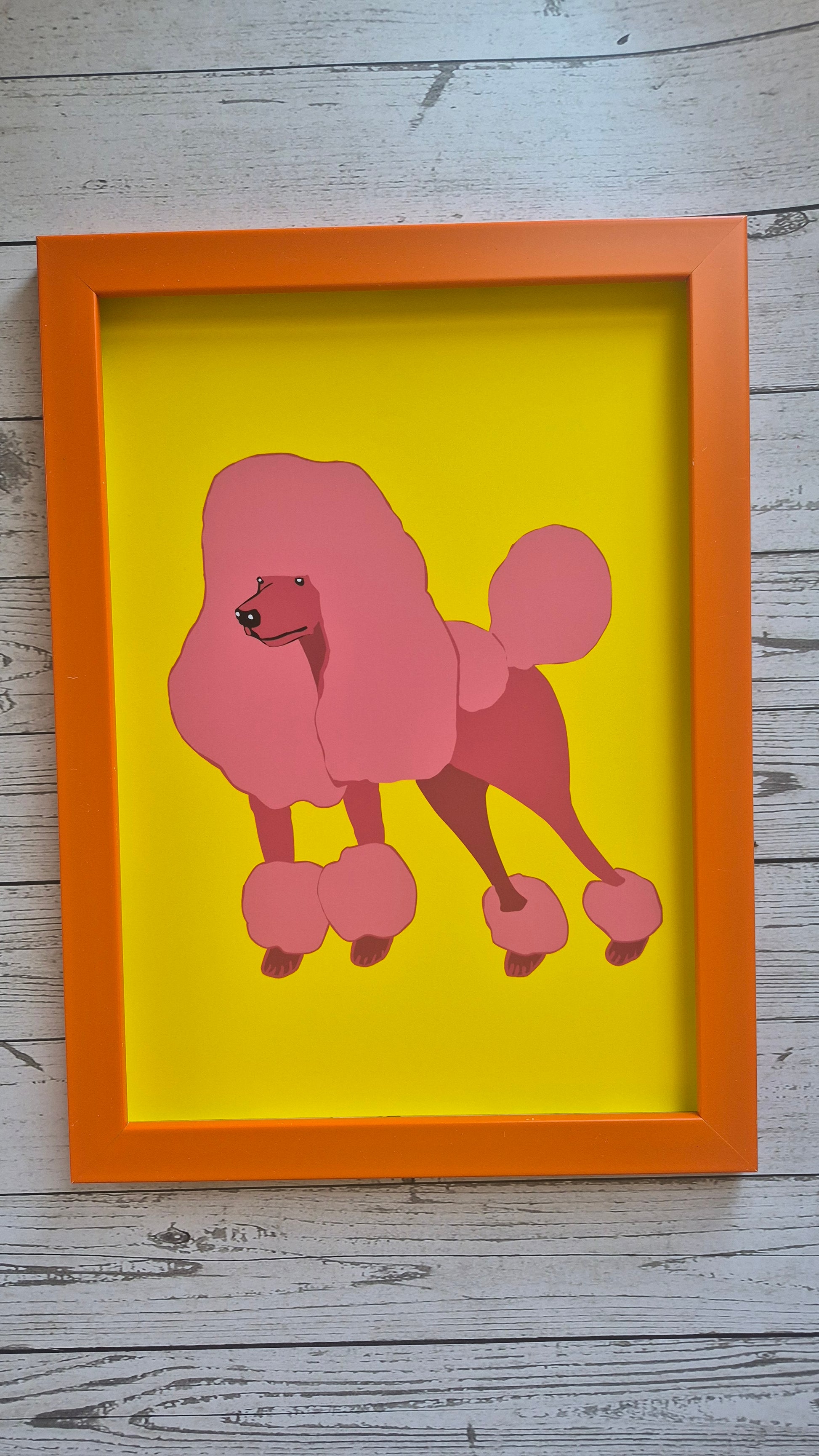 Framed artwork of a pink illustrated poodle design print on a solid yellow background in an orange frame.
