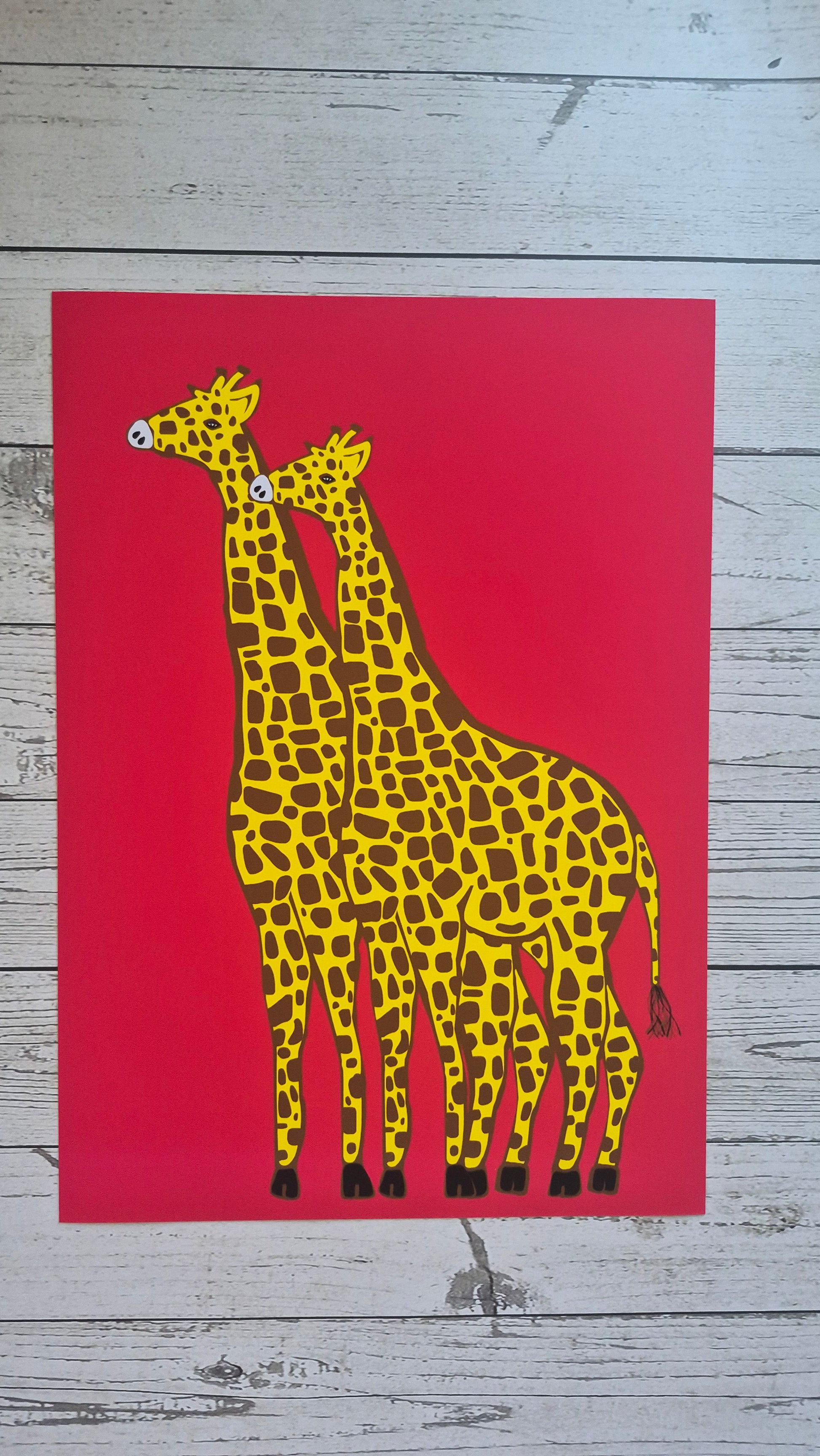 Yellow giraffe print featuring two giraffes on a solid red background. 