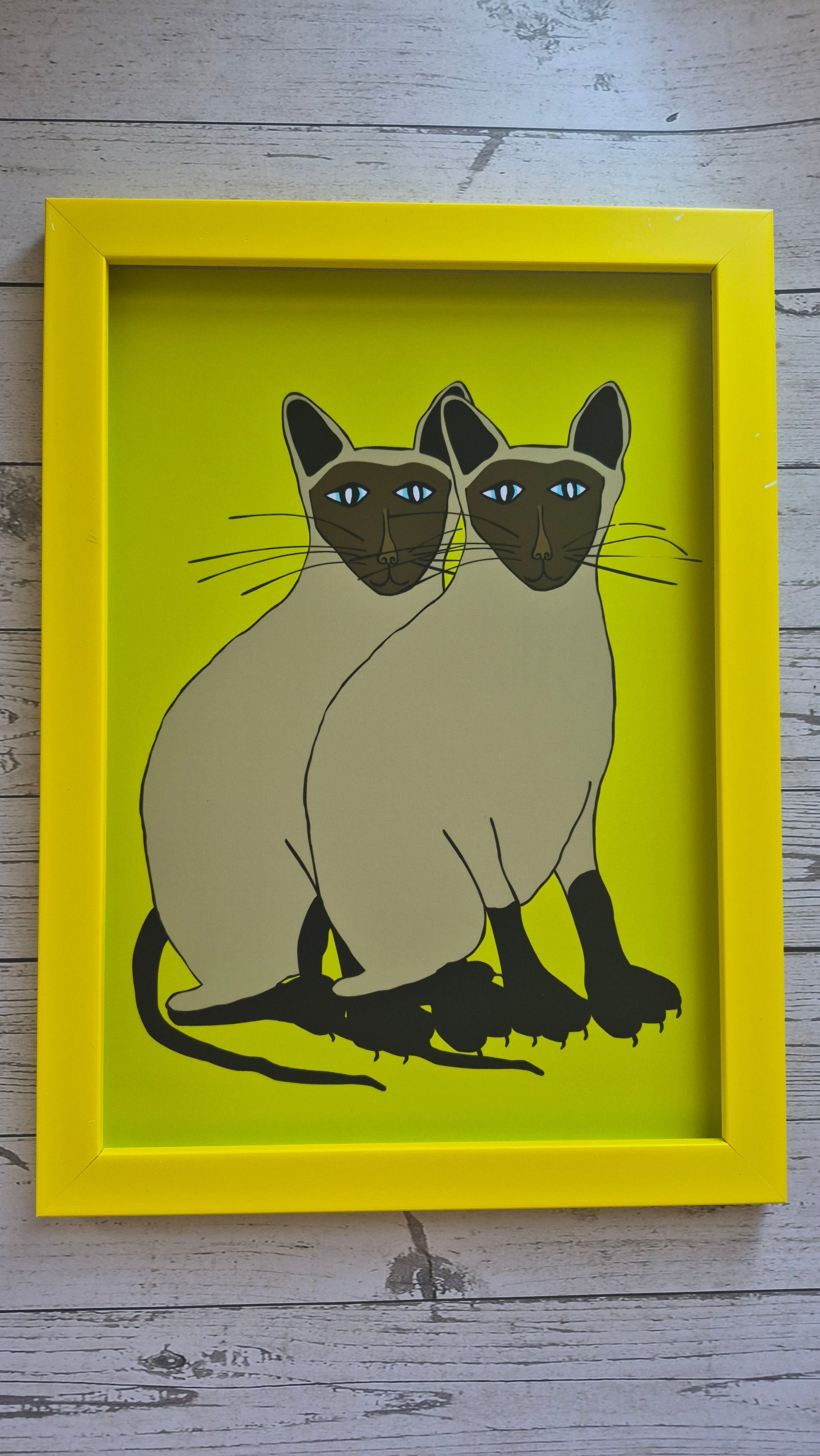 Framed illustration of two Siamese cats on a lime green background
