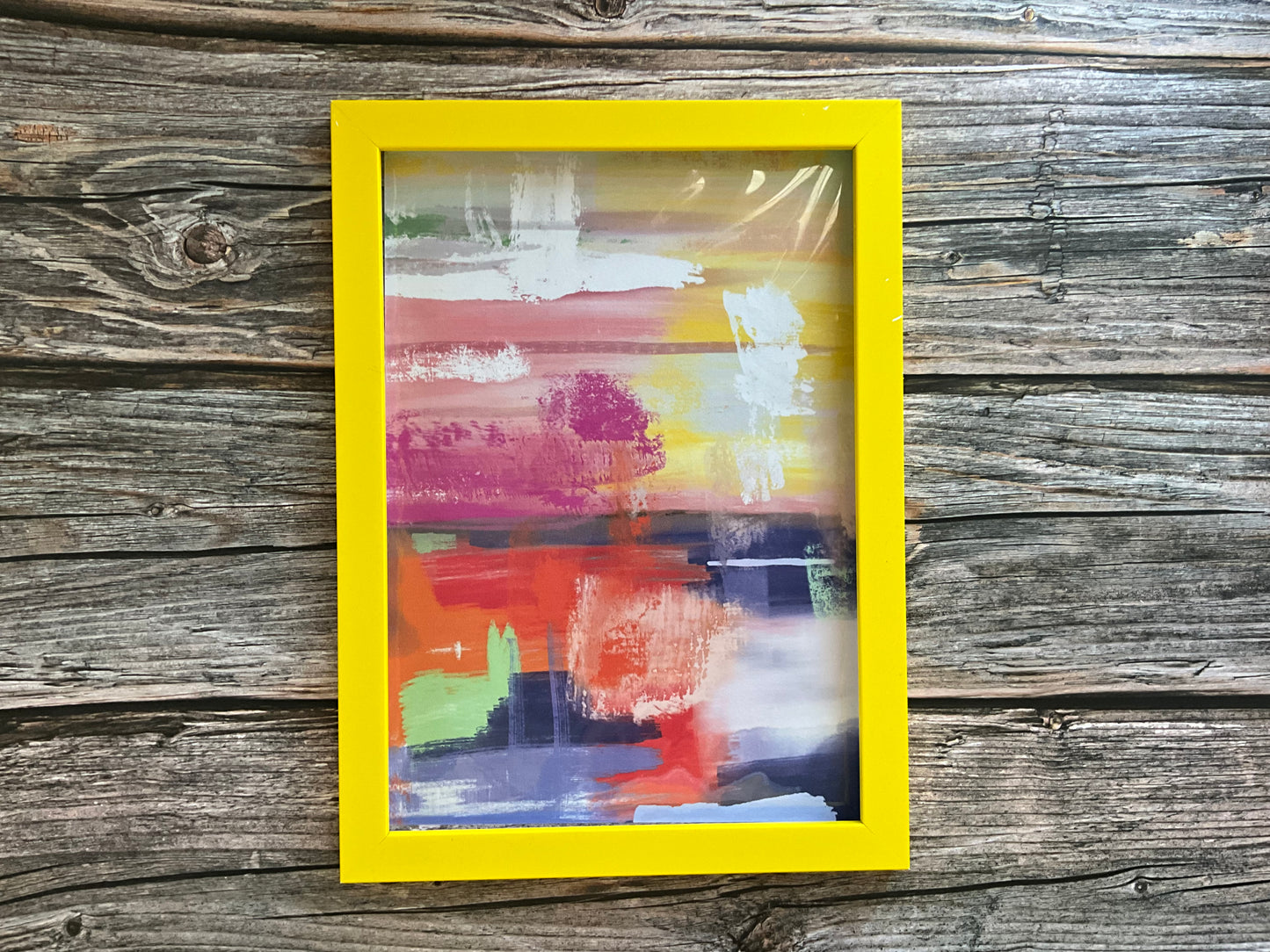 Abstract painting in a yellow frame on a wooden surface