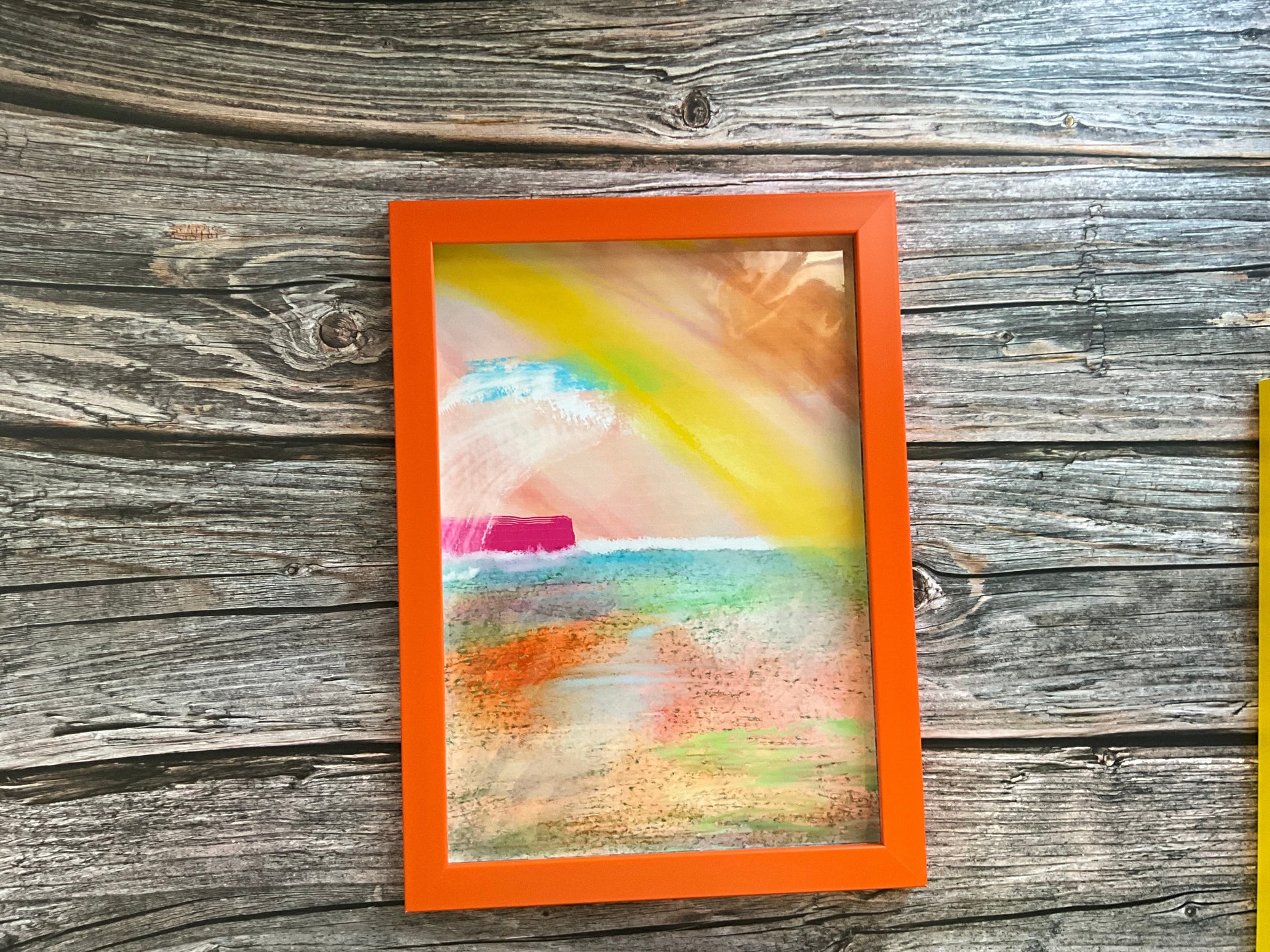 Framed abstract artwork with an orange border on a wooden surface
