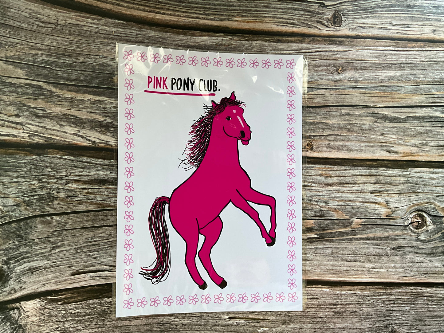Pink horse print with the text ‘pink pony club’ White background with a pink flower outline.