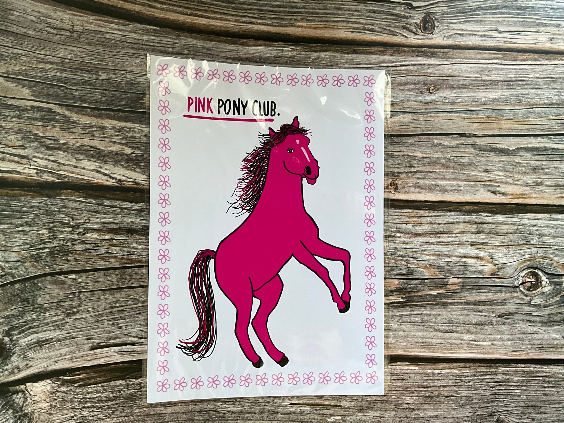 Pink horse print with the text ‘pink pony club’ White background with a pink flower outline.