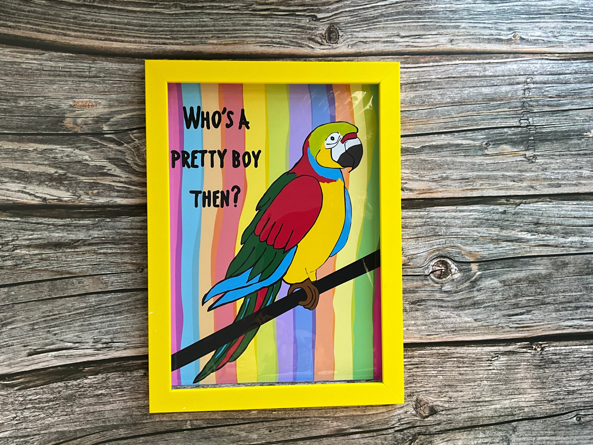 Colorful parrot illustration with text in a yellow frame on a wooden background