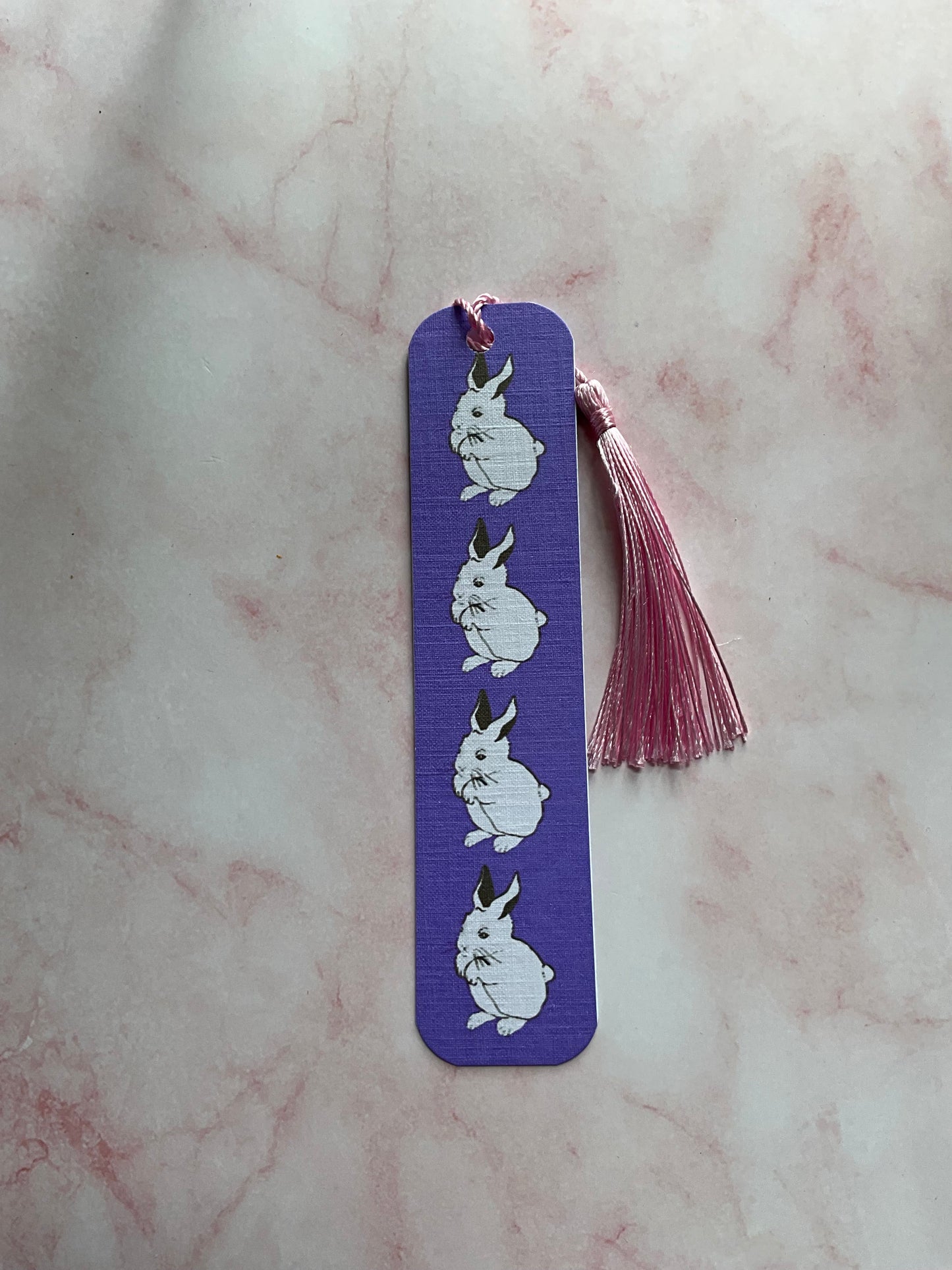 Purple bookmark with white bunny prints on a marble surface