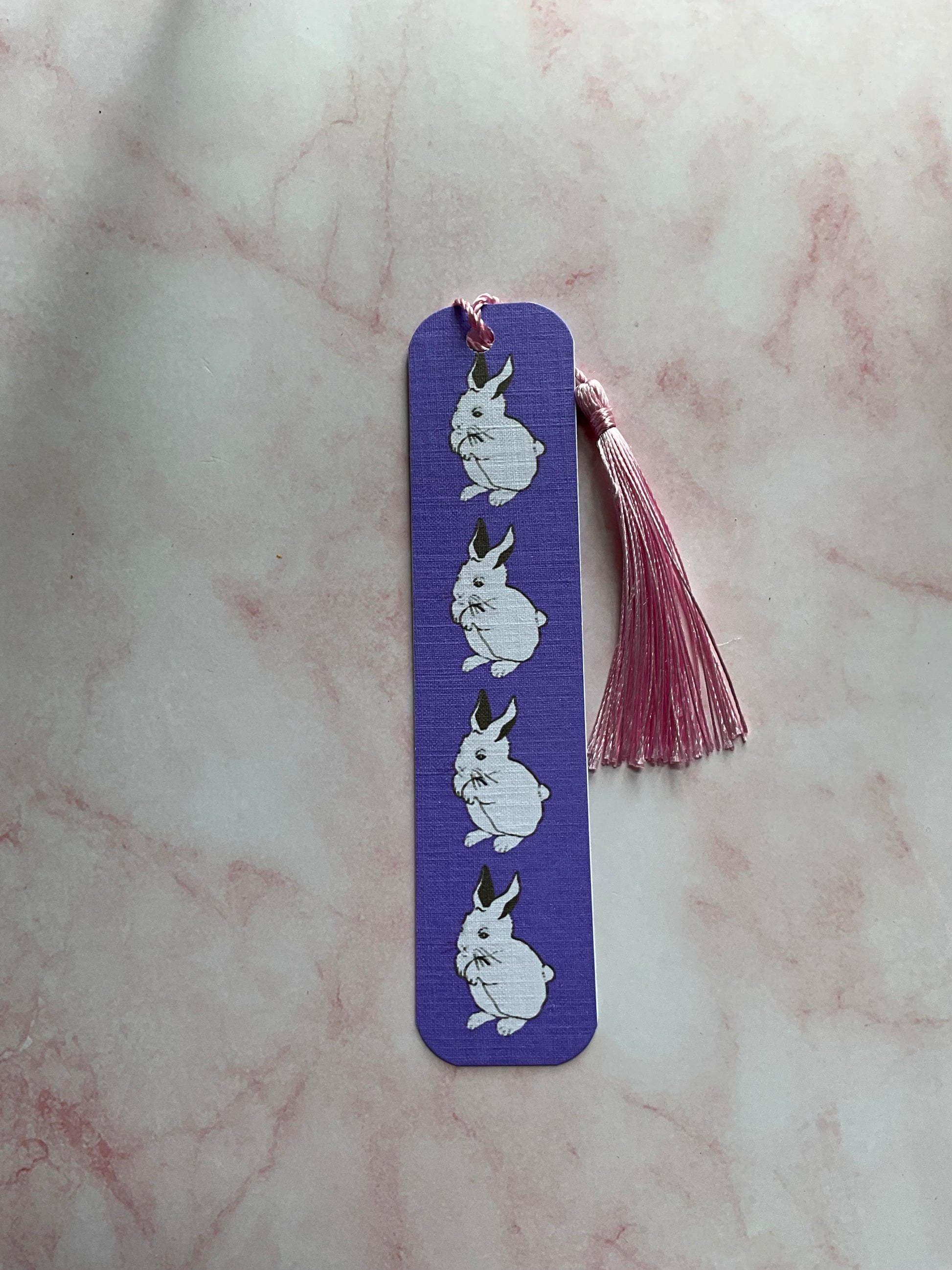 Purple bookmark with white bunny prints on a marble surface