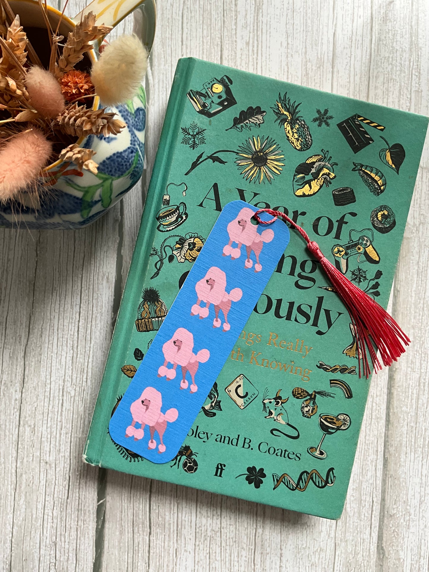 Book with a pink poodle bookmark and pink tassel on top of a book.
