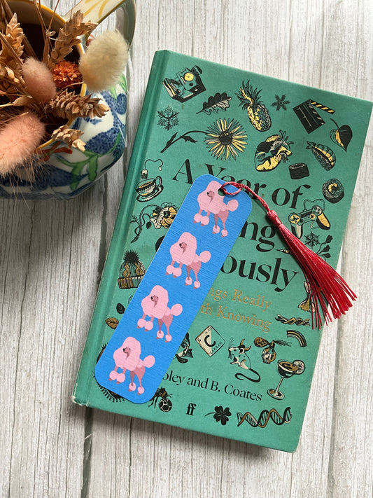 Book with a pink poodle bookmark and pink tassel on top of a book.