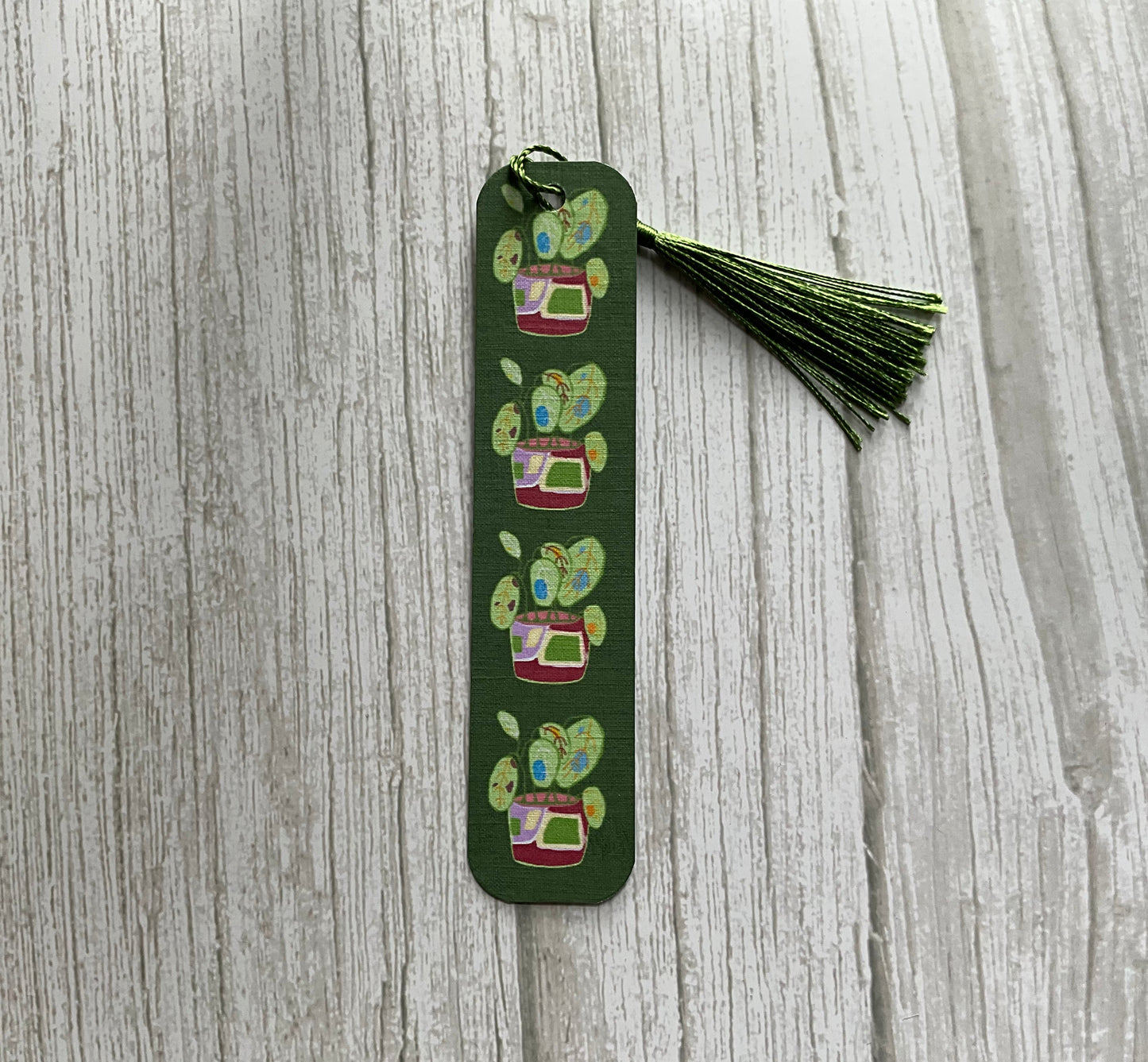 Green botanical bookmark with leafy plant designs and a silky green tassel