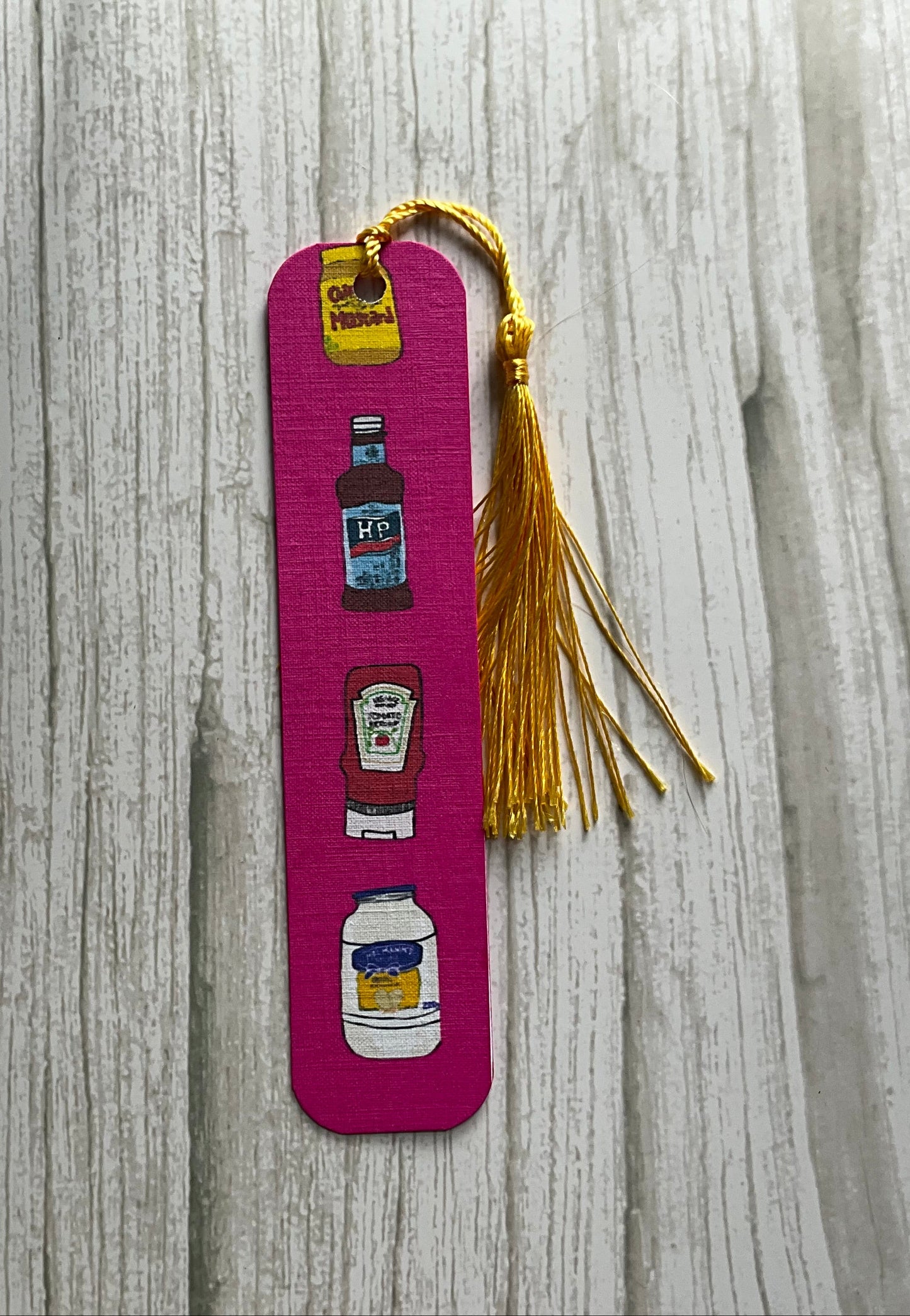 Pink condiment print bookmark with tassel on a wooden surface
