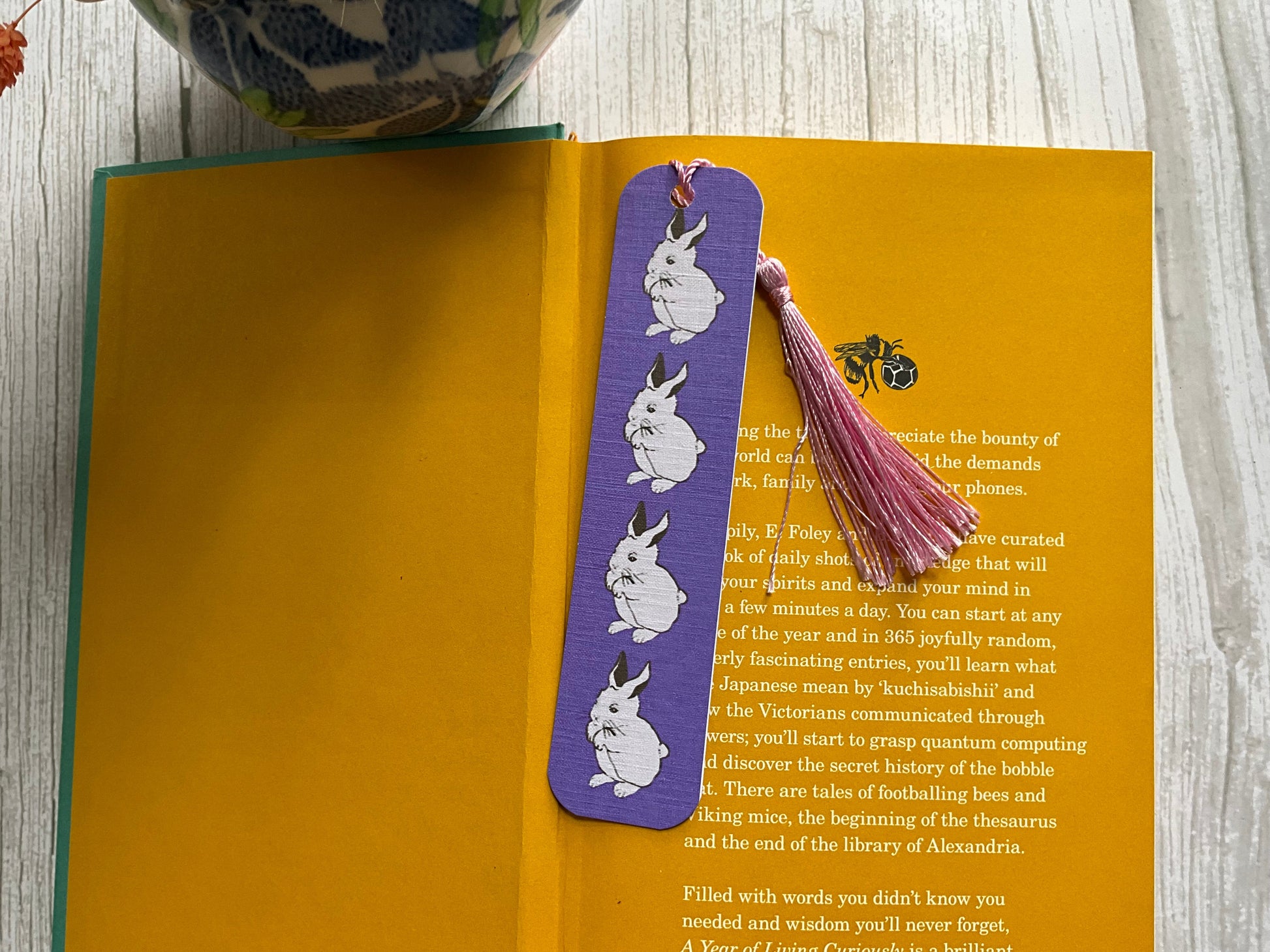 Purple bookmark with hand illustrated white bunny design on a yellow book
