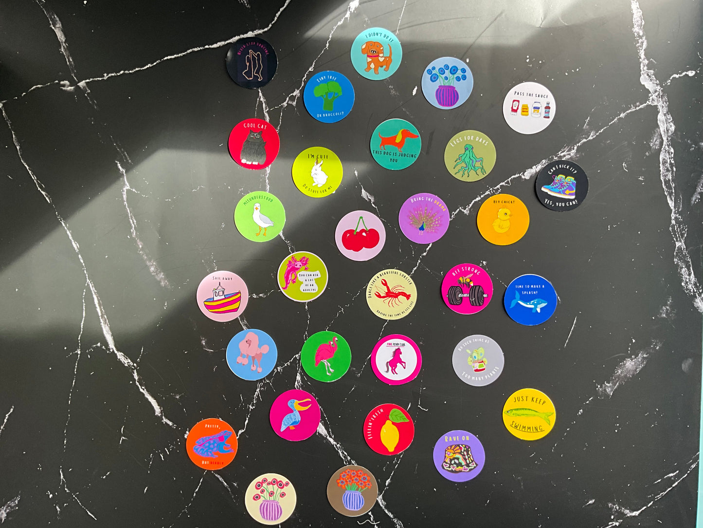 Collection of colorful round stickers on a cracked black surface