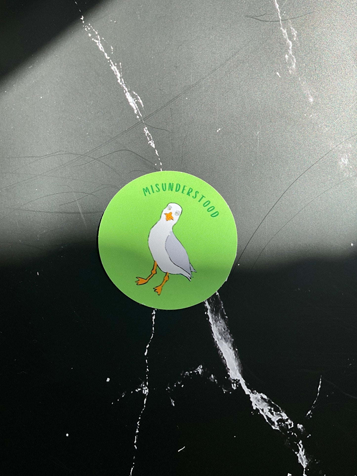 Green sticker with a seagull bird design on a marble surface