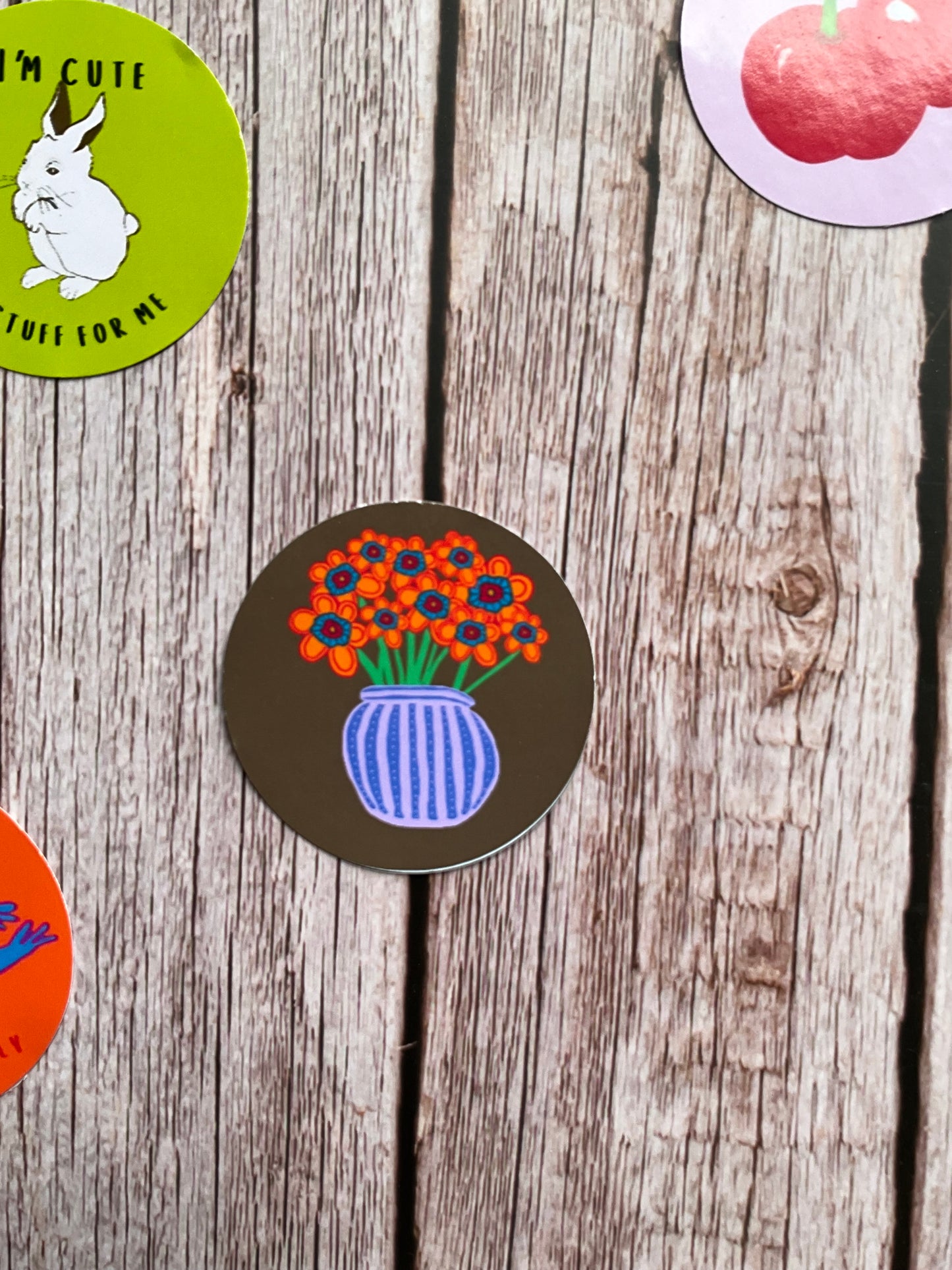 Colourful orange and blue flowers in a striped vase on a khaki green background - round vinyl sticker