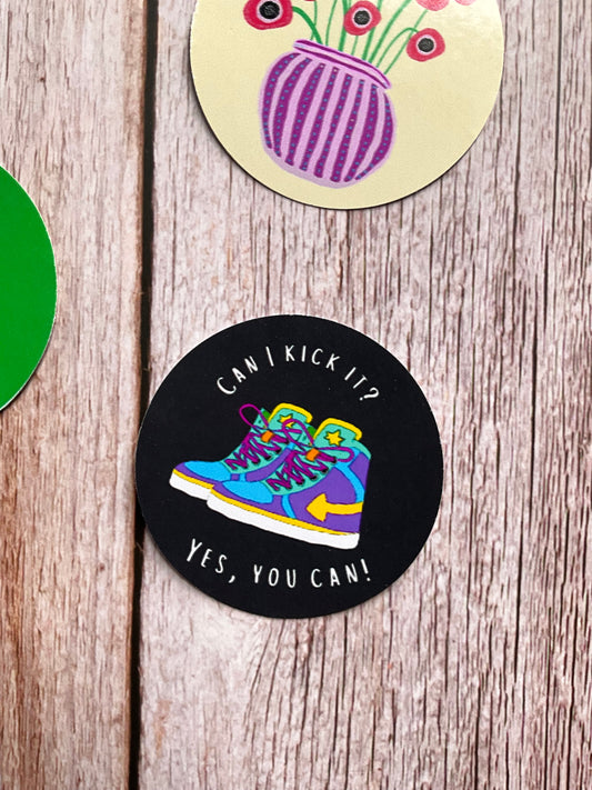 Black retro vinyl sticker with and colourful hi top trainer design on a wooden surface.