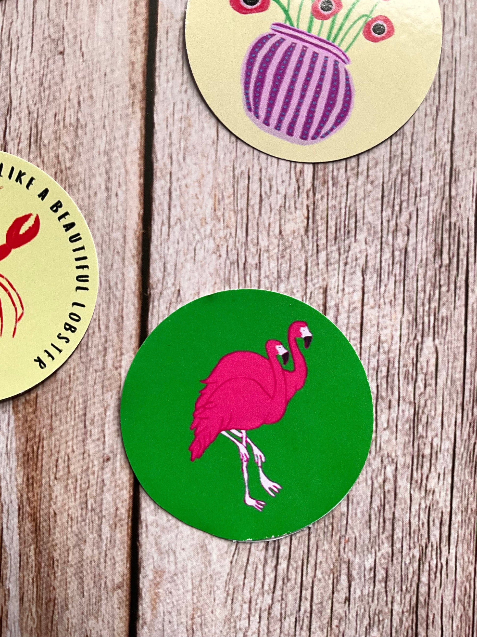 Green round vinyl sticker featuring two pink flamingos