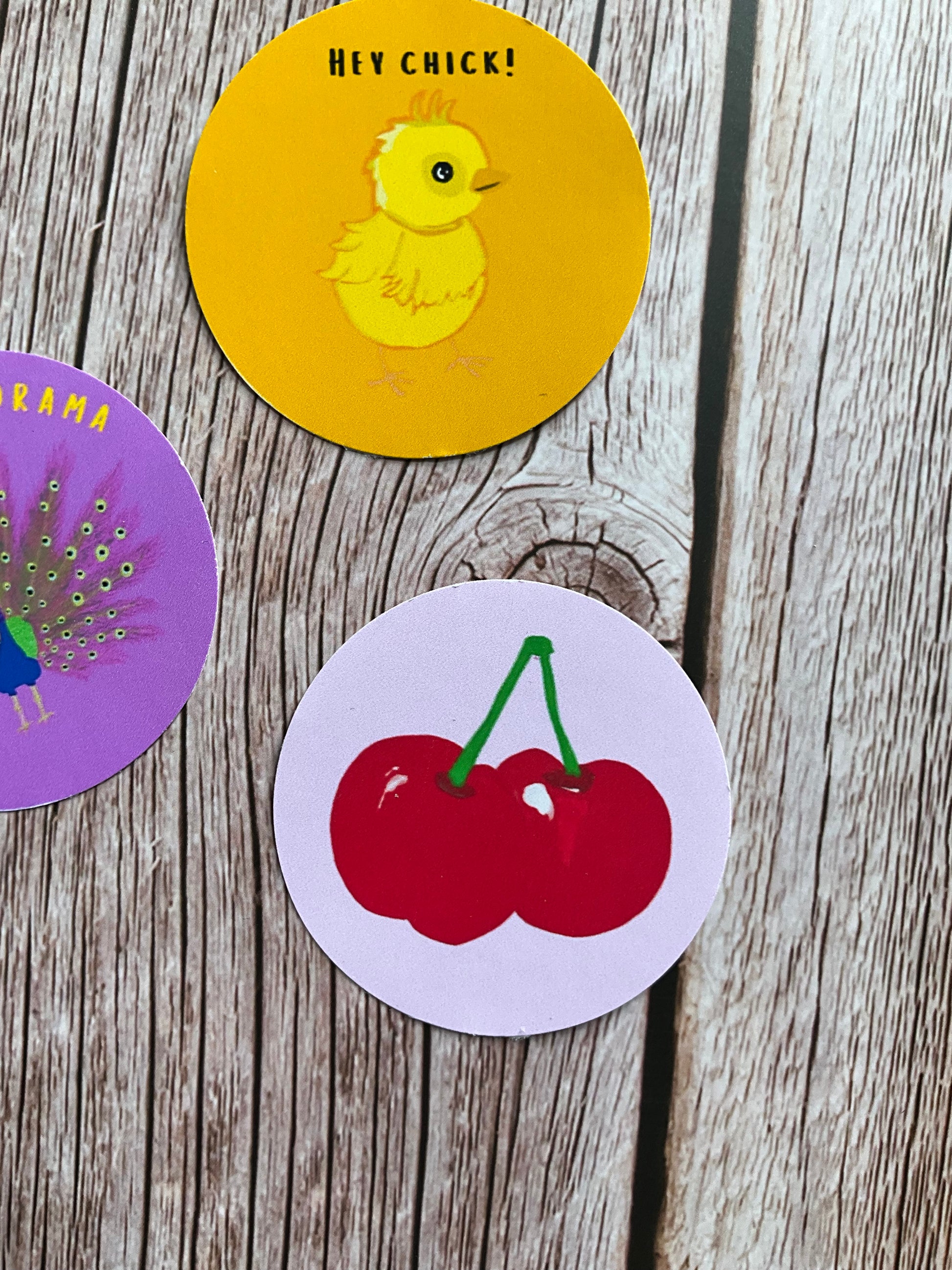 Colourful vinyl sticker designs with the focus on a round pale pink one with a juicy cherry design