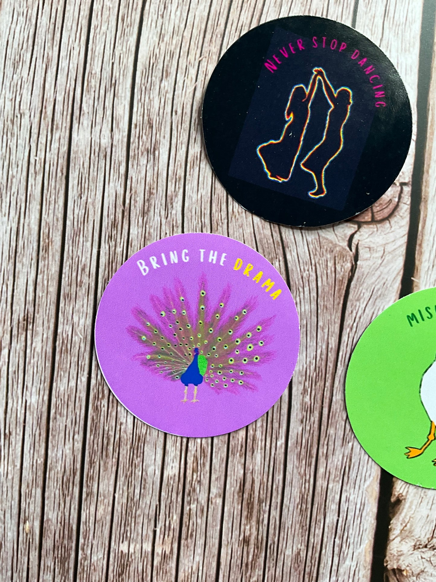 Purple round vinyl sticker with peacock design and the text ‘bring the drama’