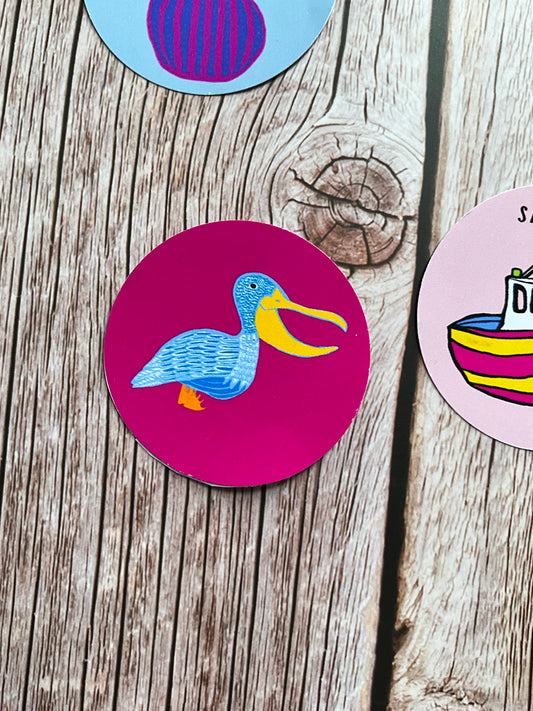 Deep pink round vinyl sticker featuring a blue and white patterned pelican illustration
