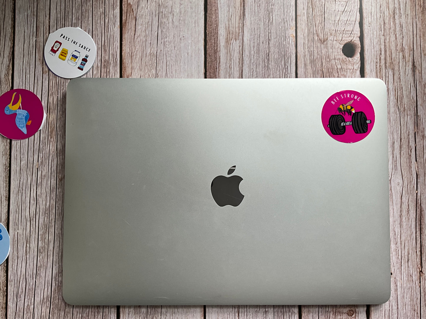 Silver laptop with Apple logo on a wooden surface with stickers around it