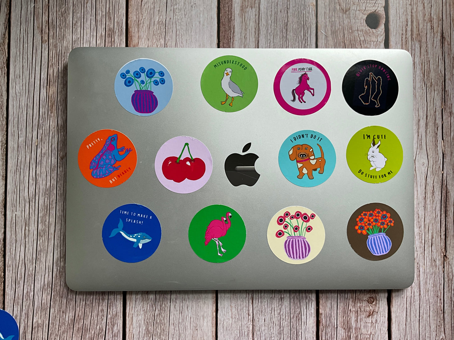 Laptop with various colorful stickers on a wooden surface